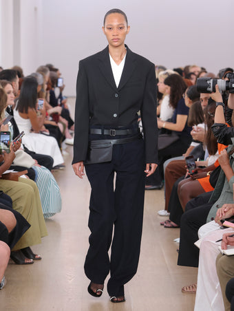 Model walking Proenza Schouler SS24 Runway in Talia T-shirt In White Eco Cotton Jersey, Joey Pant In Navy Brushed Cotton Suiting, Sandis Jacket In Black Viscose Wool Suiting, Zip Belt Bag In Black Calf Leather, Tee Toe Ring Sandals  In Black + Cream Nappa Lux