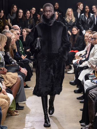 Model Walking in Proenza Schouler Fall Winter 2024 Runway Show Wearing Fiona Coat in Black Sheared Toscana, City Bag in Black Eel, and  Park Loafers in Black Slick Nappa