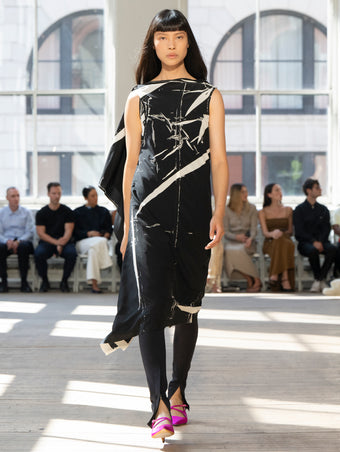 Image of model walking Proenza Schouler SS25 Runway wearing Ondine Dress in Garment Printed Silk Viscose in Black and Zip Legging in Technical Jersey in Black and Silo Bag in Black Nappa  in BLACK and Slash Slingback Pump in Fuschia