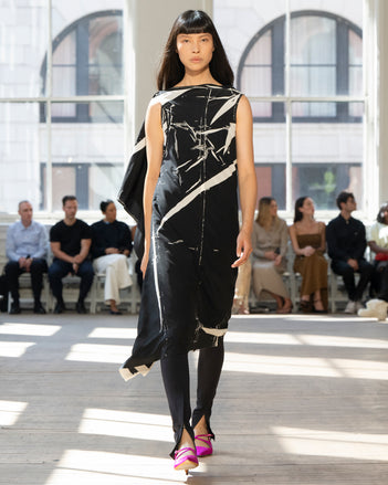 Image of model walking Proenza Schouler SS25 Runway wearing Ondine Dress in Garment Printed Silk Viscose in Black and Zip Legging in Technical Jersey in Black and Silo Bag in Black Nappa  in BLACK and Slash Slingback Pump in Fuschia