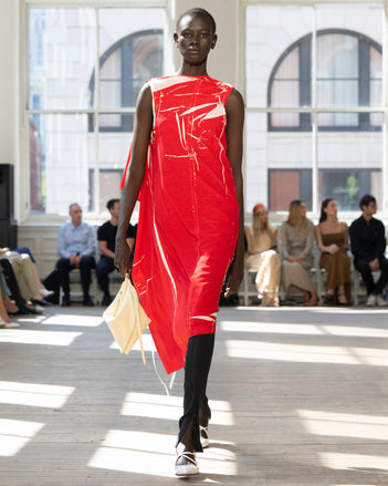 Image of model walking Proenza Schouler SS25 Runway wearing Ondine Dress in Garment Printed Silk Viscose in Crimson and Zip Legging in Technical Jersey in Black and Tetra Shoulder Bag in Manilla Nappa in MANILLA and Slash Slingback Pump in WHITE
