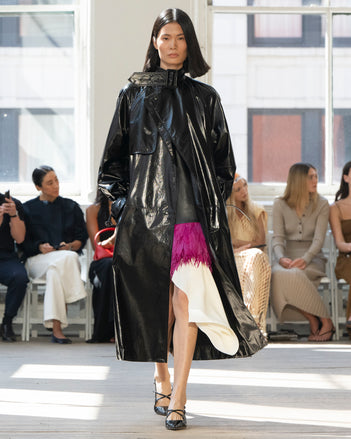 Image of model walking Proenza Schouler SS25 Runway wearing Sabina Coat in Lacquered Leather in Black and Renne Top in Textured Leather in Black and Mali Skirt in Feather Embroidery in Fuschia and Slash Slingback Pump in BLACK