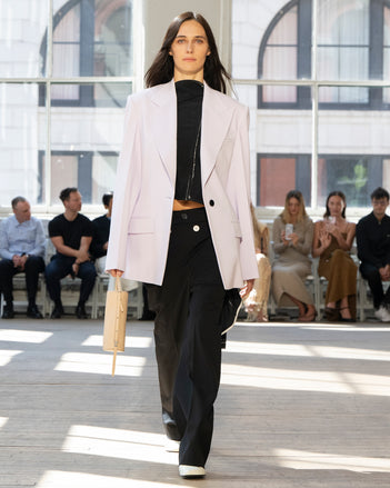Image of model walking Proenza Schouler SS25 Runway wearing Keny Jacket in Wool Gabardine in Lilac and Ondine Top in Garment Printed Silk Viscose in Black and Oliver Pant in Wool Gabardine in Black and Silo Bag in Smoke Satin in SMOKE and Glove Shoe in WHITE