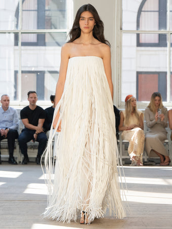 Image of model walking Proenza Schouler SS25 Runway wearing Phia Dress in Leather Silk Fringe in Ecru and Tee Thong Sandal in BLACK