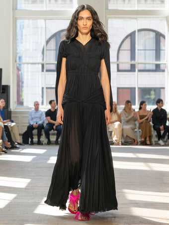 Image of model walking Proenza Schouler SS25 Runway wearing Rumi Dress in Pleated Jersey in Black and Tee Feather Thong Sandal in Fuschia