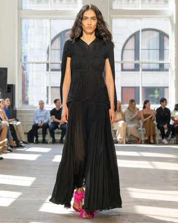 Image of model walking Proenza Schouler SS25 Runway wearing Rumi Dress in Pleated Jersey in Black and Tee Feather Thong Sandal in Fuschia