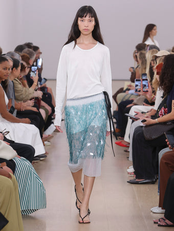 Model Walking Proenza Schouler SS24 Runway In Tina Sweater In White Cotton Silk, Lia Skirt In Embroidered Technical Organza, Tee Thong Sandals In Black Nappa Lux