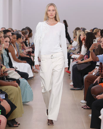 Model Walking Proenza Schouler SS24 Runway In Tina Sweater In White Cotton Silk, Ellsworth Jean In Ecru Denim, Park Shoulder Bag In Optic White Ostrich Embroidered Nylon, Tee Toe Ring Sandals In Black + Cream Nappa Lux