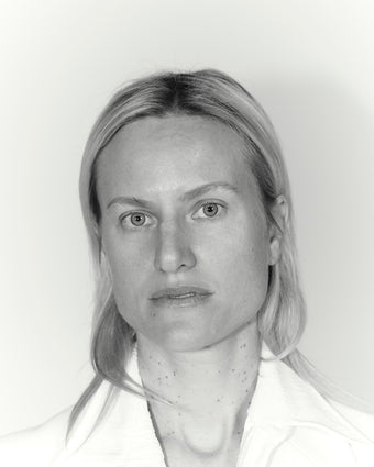 black and white image of a model with short blond hair looking into the camera wearing a white suiting jacket