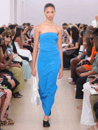 Model Walking Proenza Schouler SS24 Runway In Odette Dress In Cerulean Silk Viscose, Net Sling Bag In Optic White Tulle, Soft Square Slippers In Black Silk Satin