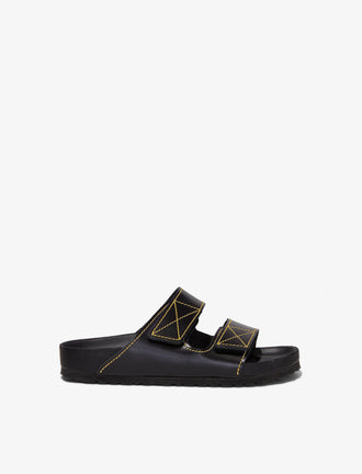 Proenza Schouler side image of Birkenstock collaboration Arizona Slides in black with yellow contrast stitching