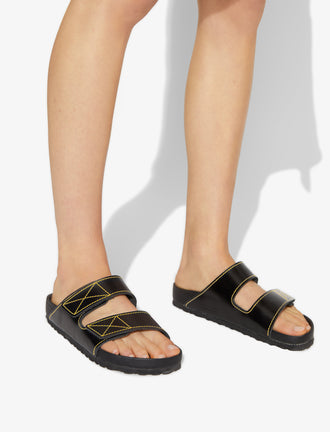 Proenza Schouler image of model wearing Birkenstock collaboration Arizona Slides in black with yellow contrast stitching