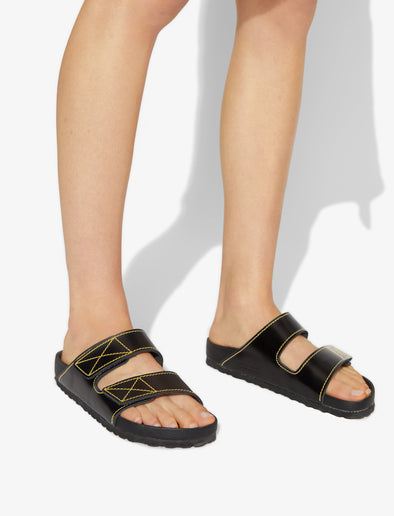 Proenza Schouler image of model wearing Birkenstock collaboration Arizona Slides in black with yellow contrast stitching