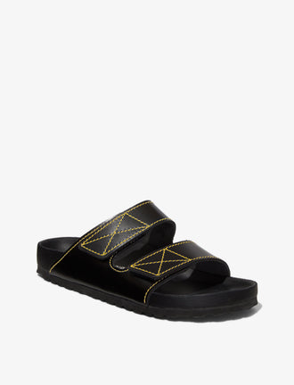 Proenza Schouler front 3/4 image of Birkenstock collaboration Arizona Slides in black with yellow contrast stitching
