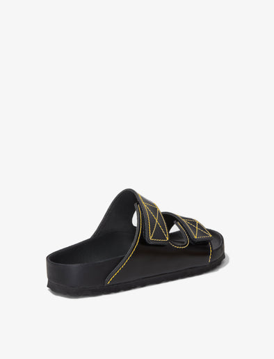 Proenza Schouler back 3/4 image of Birkenstock collaboration Arizona Slides in black with yellow contrast stitching