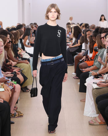 Model Walking Proenza Schouler SS24 Runway In Stella Sweater In Black Cashmere, Joey Pant In Navy Brushed Cotton Suiting, Flip Shoulder Bag In Black Silk Satin, Tee Toe Ring Sandals In Cream + Black Nappa