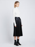 Side image of model in Faux Leather Pleated Skirt in black