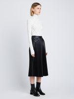 Side image of model in Faux Leather Pleated Skirt in black
