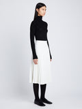Side image of model in Faux Leather Pleated Skirt in white