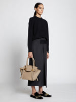 Image of model carrying Small Pipe Bag in LIGHT TAUPE
