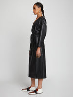 Side full length image of model wearing Faux Leather Wrap Dress in BLACK