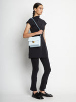 Image of model carrying Embossed Croc Dia Day Bag in pale blue