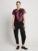 Front full length image of model wearing Faux Leather Twisted Top in PLUM