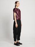 Side full length image of model wearing Faux Leather Twisted Top in PLUM