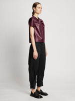 Side full length image of model wearing Faux Leather Twisted Top in PLUM