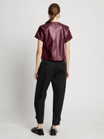 Back full length image of model wearing Faux Leather Twisted Top in PLUM