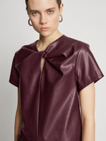 Detail image of model wearing Faux Leather Twisted Top in PLUM