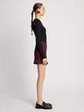 Side full length image of model wearing Faux Leather Smocked Mini Skirt in PLUM
