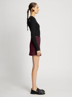 Side full length image of model wearing Faux Leather Smocked Mini Skirt in PLUM