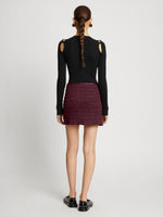 Back full length image of model wearing Faux Leather Smocked Mini Skirt in PLUM