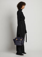 Image of model carrying Small Grainy Leather Pipe Bag in navy/red