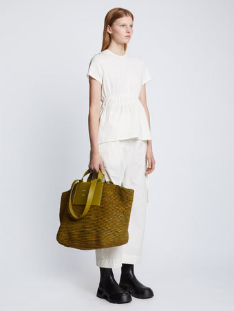 Image of model carrying XL Morris Raffia Tote in MOSS in hand