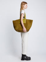 Image of model carrying XL Morris Raffia Tote in MOSS on shoulder