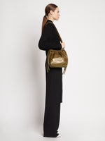 Side image of model carrying Drawstring Pouch in TRUFFLE