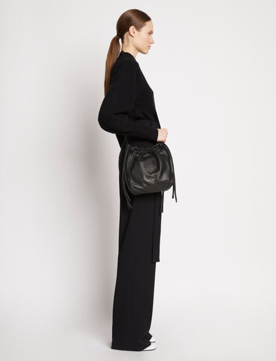 Side image of model carrying Drawstring Pouch in BLACK