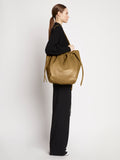 Side image of model carrying Drawstring Tote in TRUFFLE