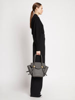 Image of model wearing Small Grainy Leather Pipe Bag in STONE