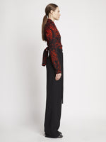 Side full length image of model wearing Painted Spiral Crepe De Chine V-Neck Top in RED MULTI
