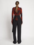 Back full length image of model wearing Painted Spiral Crepe De Chine V-Neck Top in RED MULTI