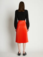 Back full length image of model wearing Faux Leather Pleated Skirt in VERMILLION