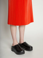 Detail image of model wearing Faux Leather Pleated Skirt in VERMILLION
