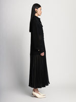 Side full length image of model wearing Sheer Pleated Flou Dress in BLACK