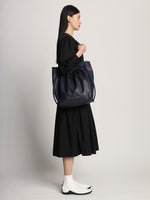 Side image of model carrying Drawstring Tote in DARK NAVY