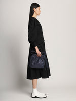 Side image of model carrying Drawstring Pouch in DARK NAVY