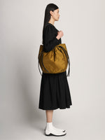 Side image of model carrying Nylon Drawstring Tote in FATIGUE