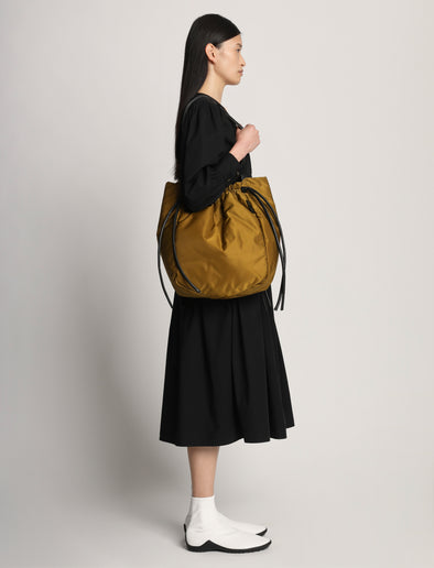 Side image of model carrying Nylon Drawstring Tote in FATIGUE